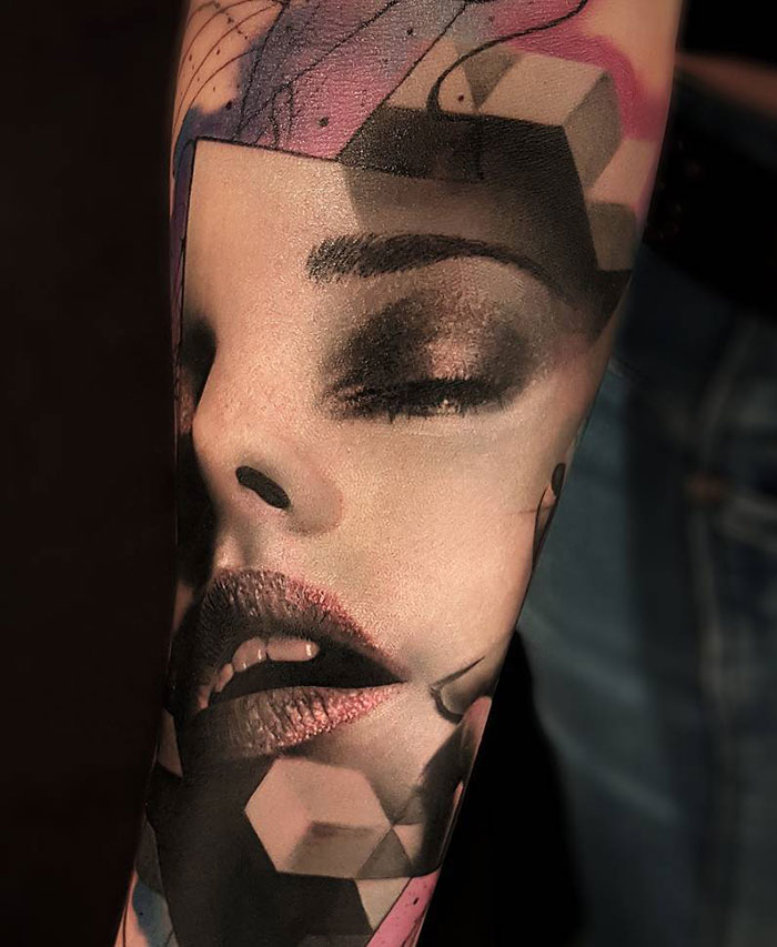 Epic optical illusion tattoo design of a woman's face with geometric elements on forearm.