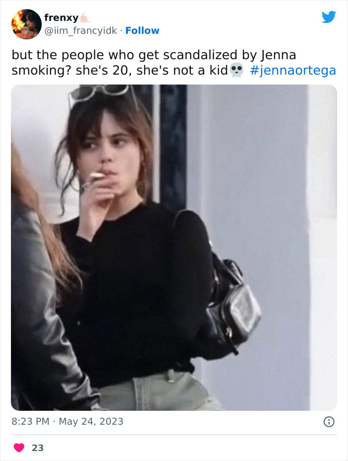 Jenna Ortega seen smoking in public, holding a cigarette, wearing a black top and green pants.