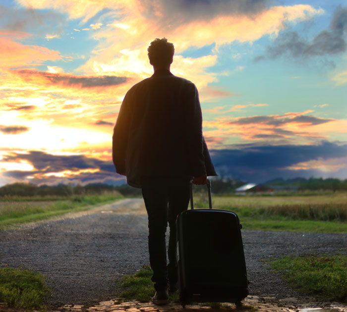 Man with a suitcase walking down the road 