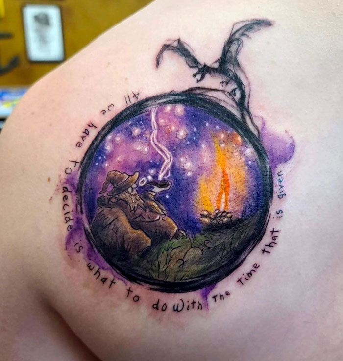 Tattoo depicting a scene inspired by Lord of the Rings with a wizard, dragon, and fiery landscape on shoulder.