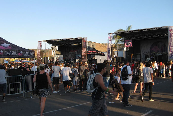 Crowd at an outdoor festival with people enjoying live music and socializing during a sunny day event.