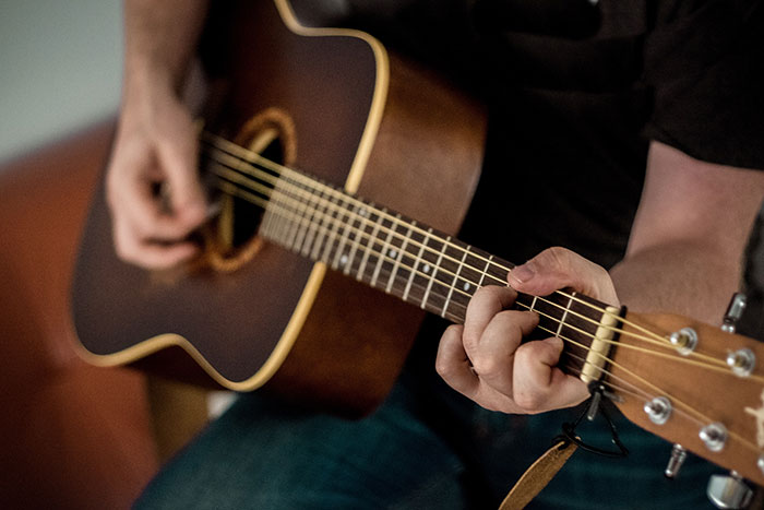 Person playing acoustic guitar showing finger placement, related to embarrassing things internet users told to impress.