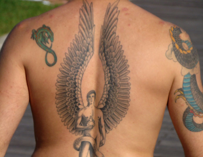 Tattooed back showing large wings and a figure, illustrating one of the embarrassing things internet users told to impress others.