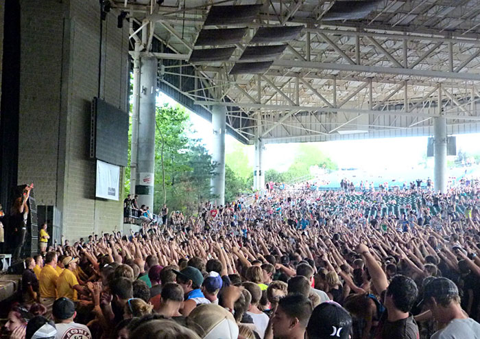 Large crowd at an outdoor concert raising hands, illustrating internet users sharing embarrassing things they said to impress.