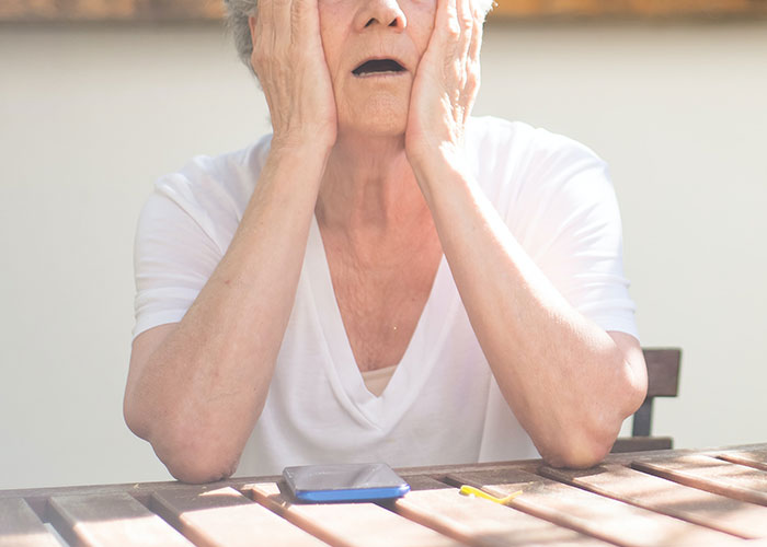 An older woman in white, looking stressed and holding her face, sits at a table with a phone, reflecting on a parenting ultimatum. An older woman in white, looking stressed and holding her face, sits at a table with a phone, reflecting on a parenting ultimatum.