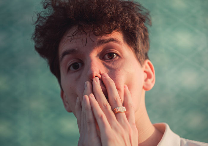 Young man covering his mouth in shock, representing the disturbing secrets people uncovered about someone close to them.
