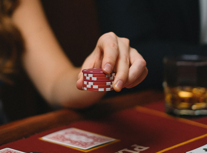 Person holding red poker chips at a casino table, symbolizing deeply disturbing secrets revealed about someone close.