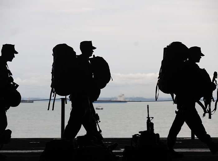 Silhouettes of soldiers carrying backpacks near water, symbolizing people revealing deeply disturbing secrets about someone close.