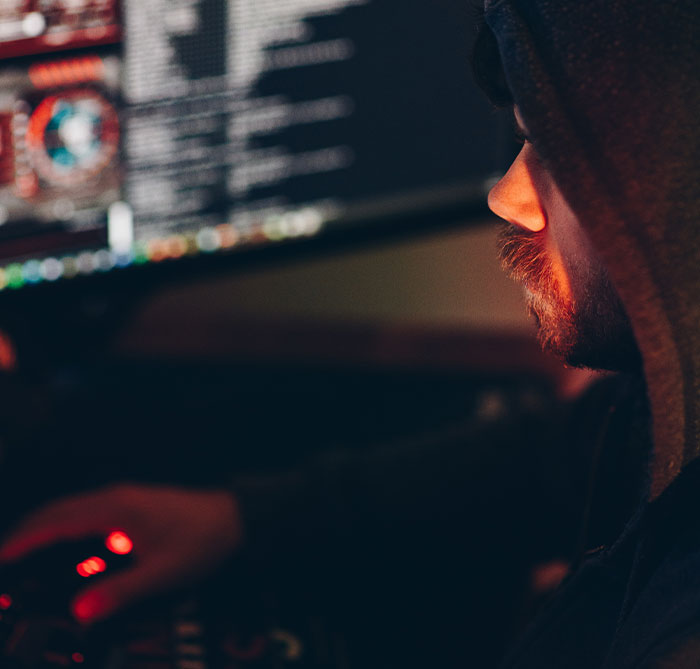 Person in a dark hoodie uncovering deeply disturbing secrets about someone close to them while working on a computer.
