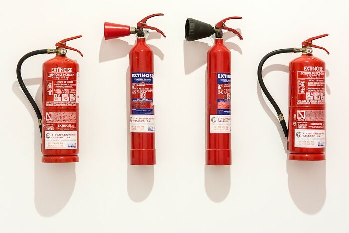 Four red fire extinguishers mounted on a white wall, illustrating items people have learned never to buy cheap.