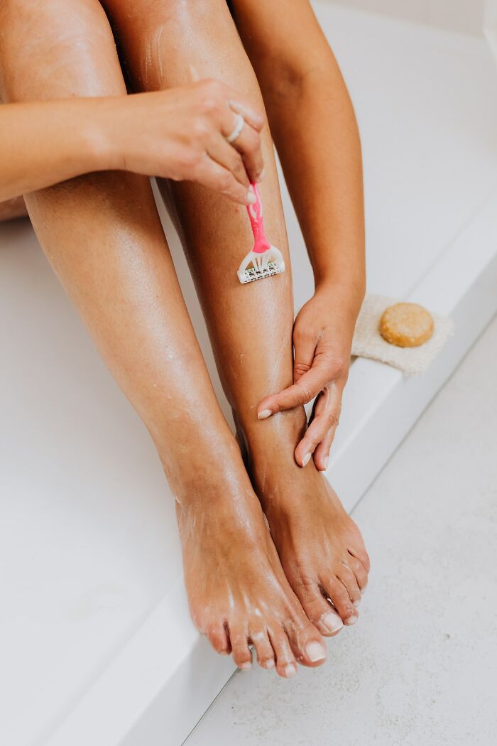 Person shaving legs with a pink razor, highlighting things people have learned never to buy cheap from an online community.