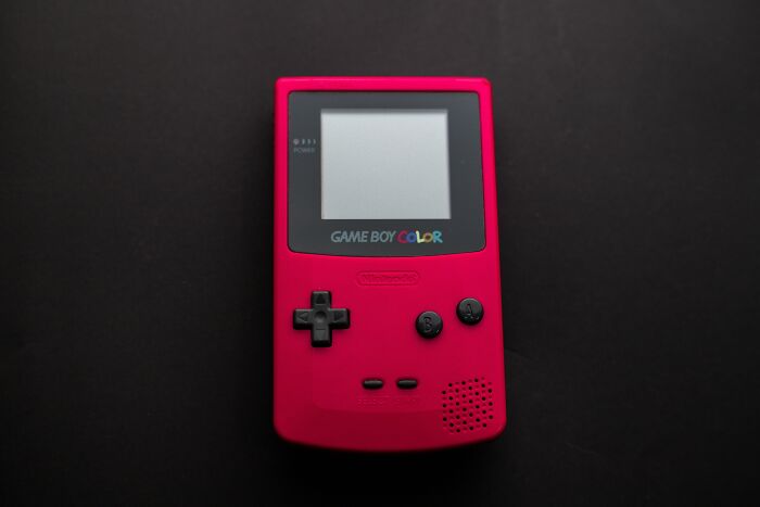 Red Game Boy Color placed on a black table, showcasing one of the old gadgets that were trendsetters of their time.