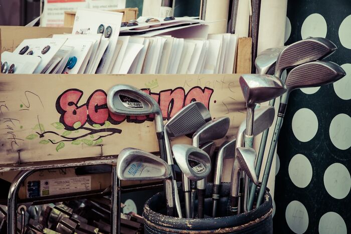 Golf clubs in a used store bucket, illustrating common things people have learned never to buy cheap for quality reasons.