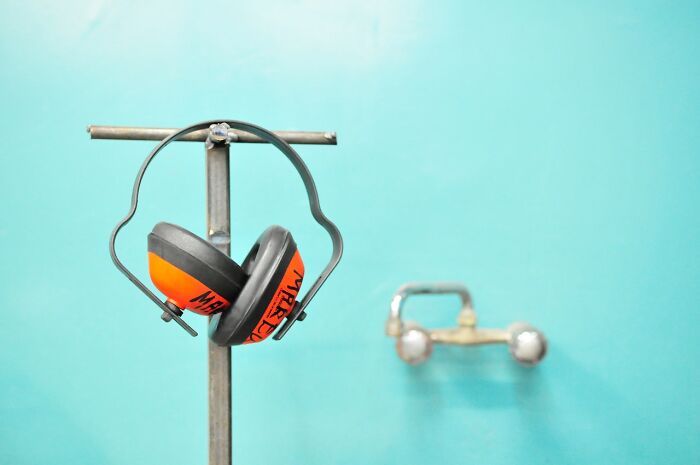 Orange and black safety earmuffs hanging on metal rack, illustrating things people have learned never to buy cheap.