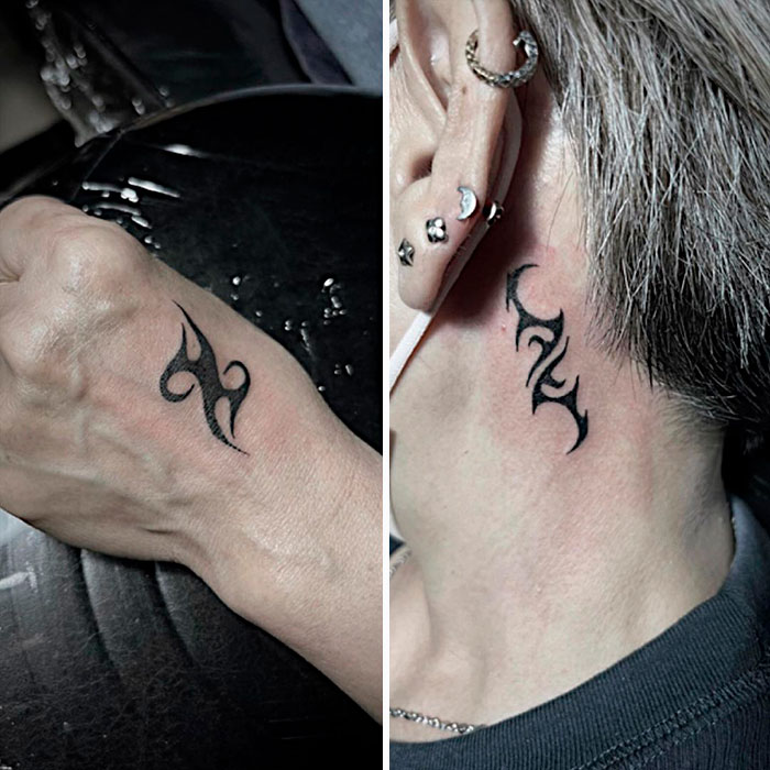 Tribal tattoos on wrist and behind ear, showcasing black ink designs.