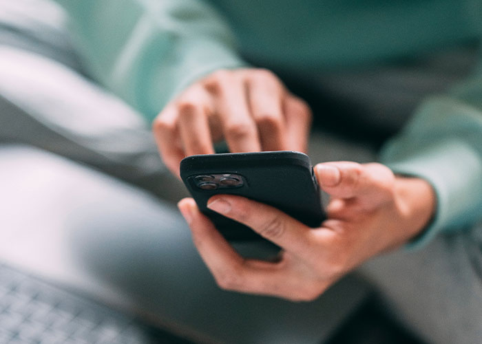 Person holding smartphone, browsing through unique college courses on screen related to rare college courses and studies.