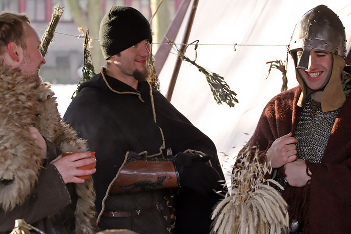 Three men dressed in Viking costumes enjoying a reenactment scene with traditional clothing and armor.