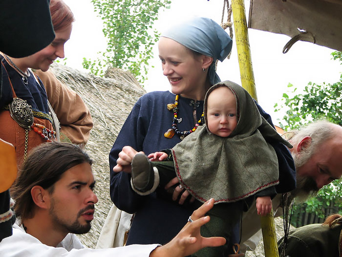 Group of people dressed in Viking clothing holding a baby, illustrating interesting and little-known facts about Vikings.