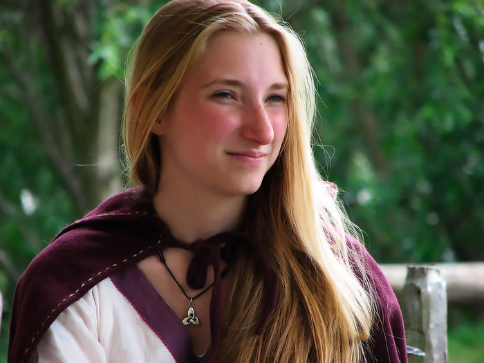 Young woman dressed in Viking-style clothing with a cloak and necklace, representing interesting Viking facts.