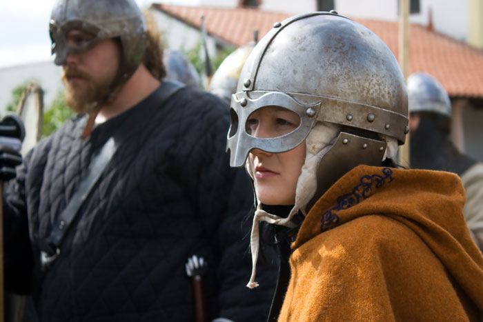 Person wearing a metal helmet and brown cloak, participating in a Viking reenactment about interesting Viking facts.