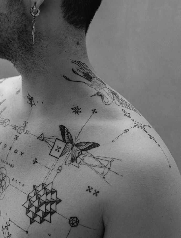 Geometric tattoo art on a person's shoulder and chest, featuring abstract and nature-inspired designs in black ink.