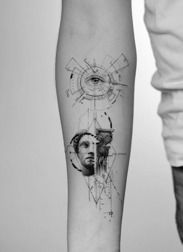 Geometric tattoo on forearm featuring an eye and classical sculpture elements in a detailed artistic design.