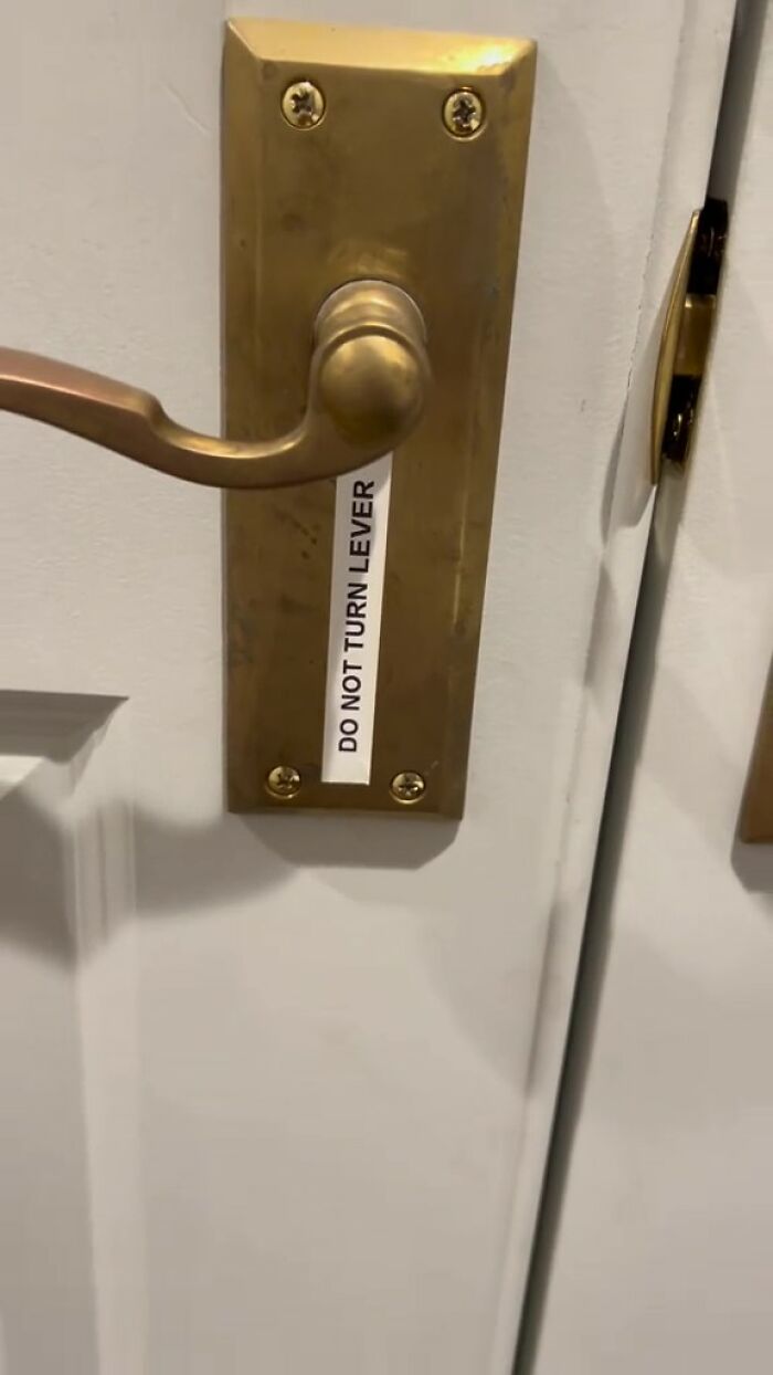 Close-up of brass door handle on white door with a label saying do not turn lever inside an Airbnb rental.