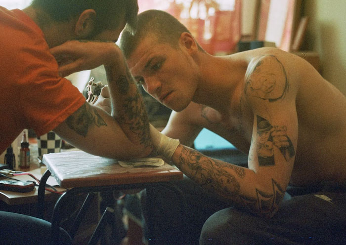 Two men in a tattoo session, one with a bold arm tattoo, exemplifying personal tattoo choices that impact relationships.