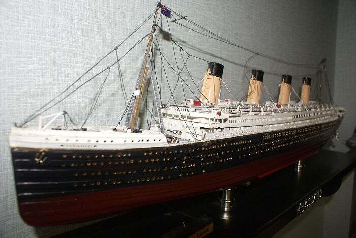 Model of an ocean liner displayed on a stand, illustrating human stupidity with a detailed ship replica indoors.