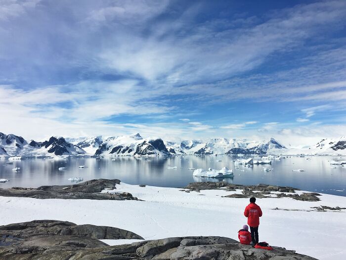 Two people in red jackets overlooking a snowy landscape with icebergs, illustrating human stupidity limits concept.