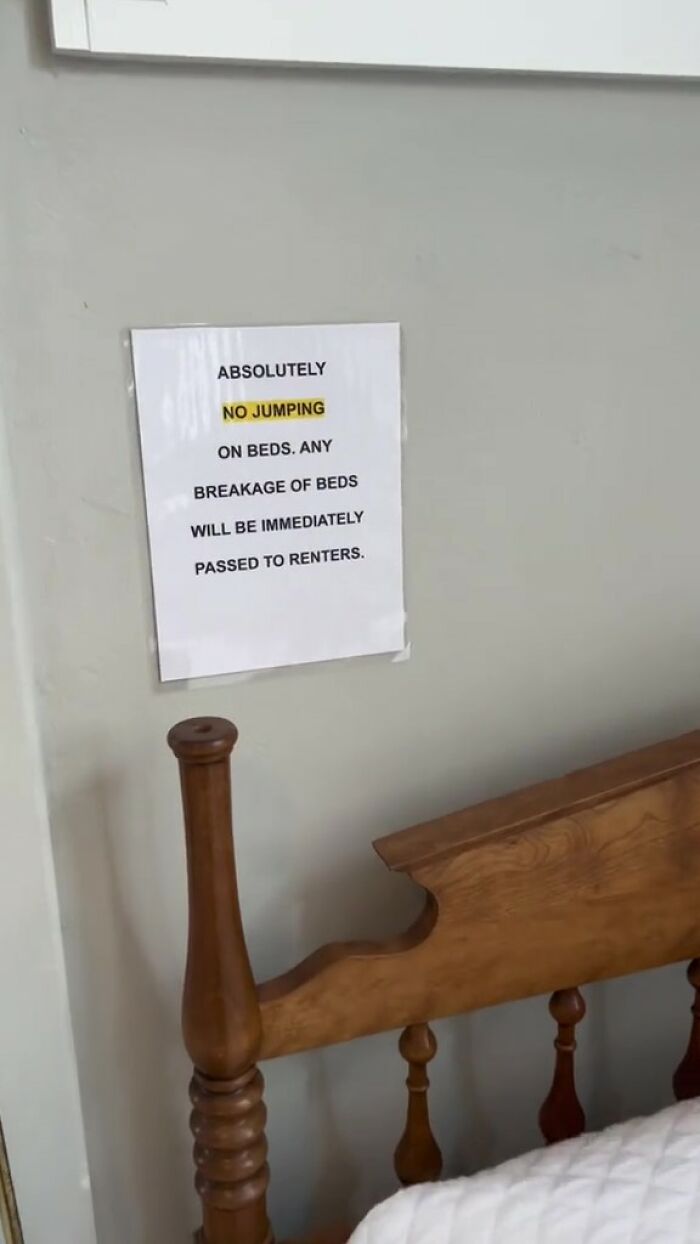 Airbnb rules note on wall above wooden bed frame warns no jumping on beds to avoid breakage.