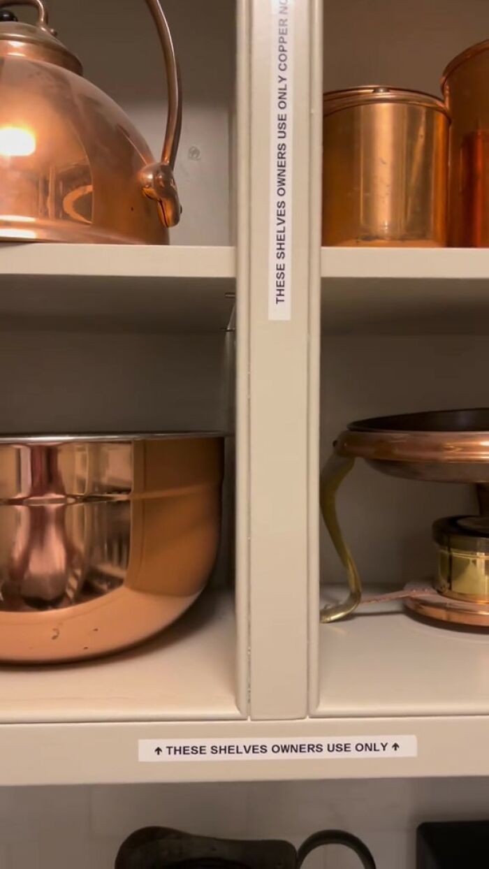 Cabinet shelves with copper pots and visible note showing Airbnb rules for owners use only.