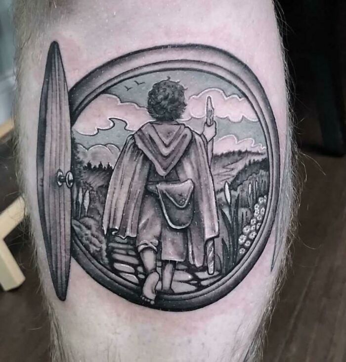 Tattoo of a hobbit leaving the Shire through a round door, inspired by Lord of the Rings.