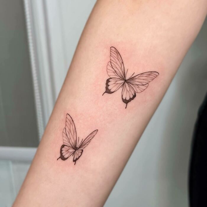 Two elegant butterfly tattoos on a forearm, showcasing intricate and colorful designs.