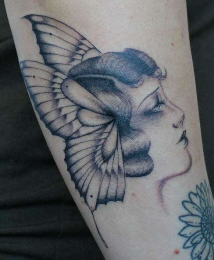 Vintage-style butterfly tattoo with a woman's profile on skin.