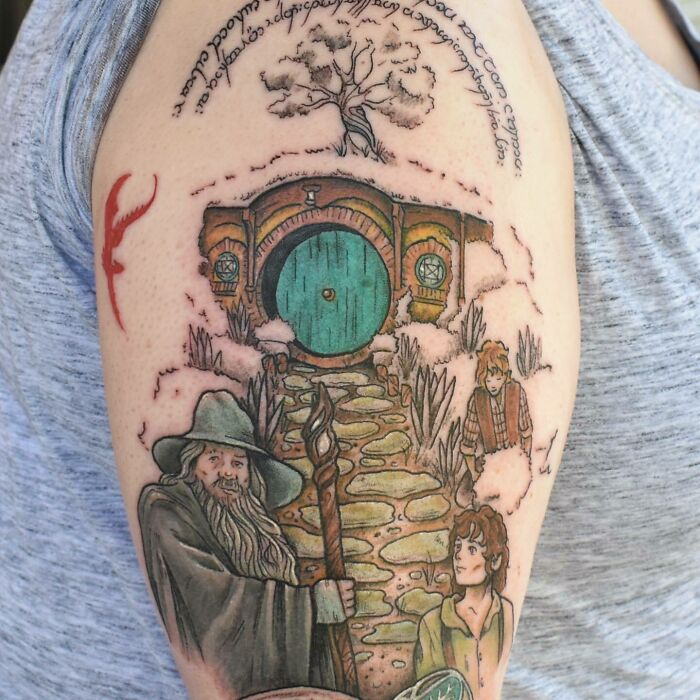 Lord of the Rings tattoo featuring characters and iconic Shire door on arm.