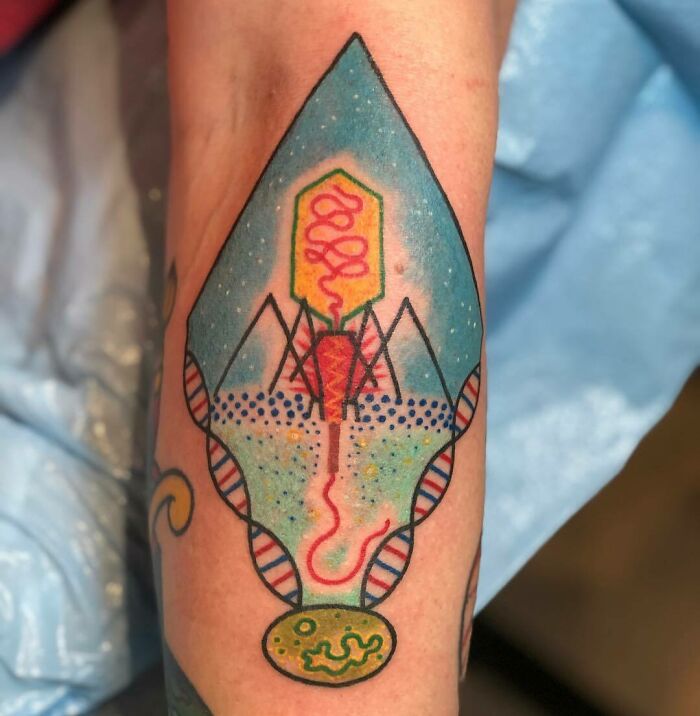Colorful science tattoo of a bacteriophage design on forearm.