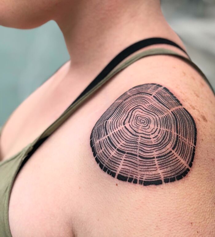 Tree tattoo on shoulder depicting tree rings, symbolizing nature's beauty.