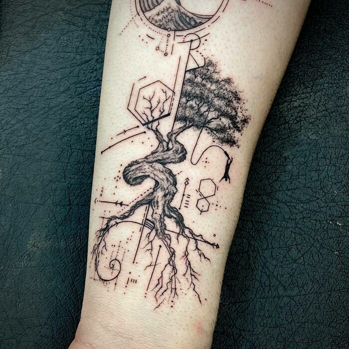 Tattoo of a tree with scientific elements and geometric shapes on a forearm.