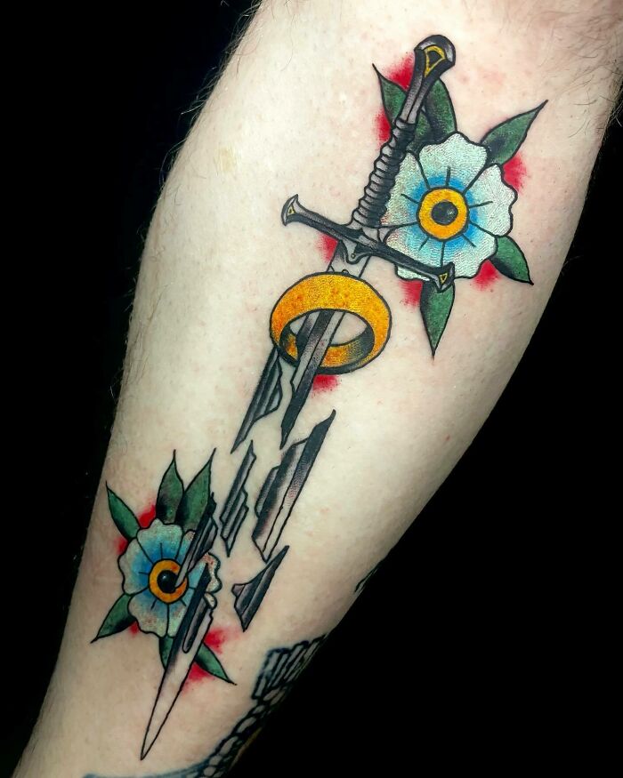 Sword and ring tattoo with flowers inspired by Lord of the Rings.