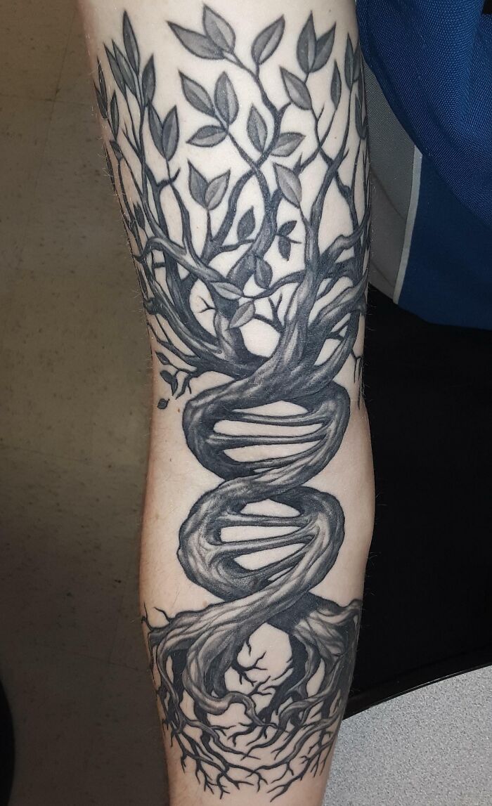 Tattoo of a tree with DNA-shaped trunk on an arm, symbolizing nature's connection to life.
