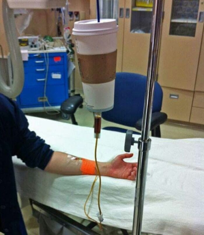A coffee meme featuring an IV drip connected to a large coffee cup, humorously implying that the person is receiving coffee intravenously. The image playfully exaggerates the idea of needing coffee as a lifeline, capturing the essence of coffee a*******n in a lighthearted and exaggerated manner.