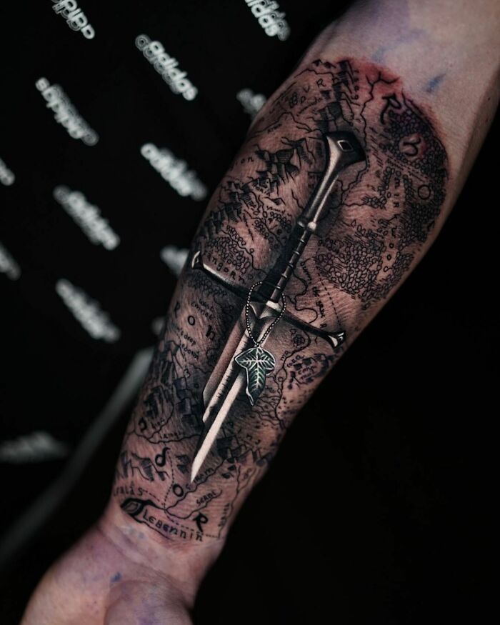 Detailed Lord of the Rings tattoo featuring a sword and map on a forearm.