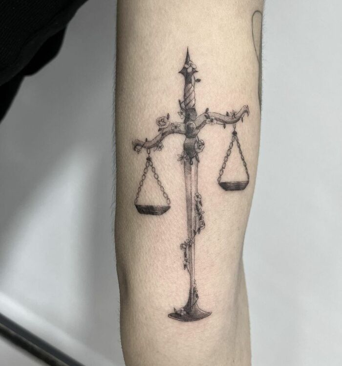 Zodiac tattoo of Libra scales intricately designed on the forearm.