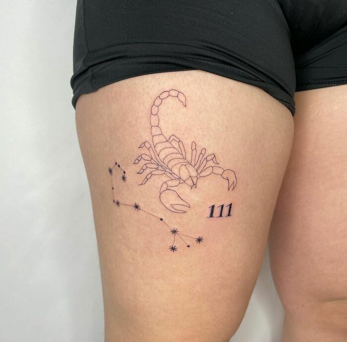 Tattoo of a scorpion with stars and number 111 on a thigh, featuring zodiac theme.