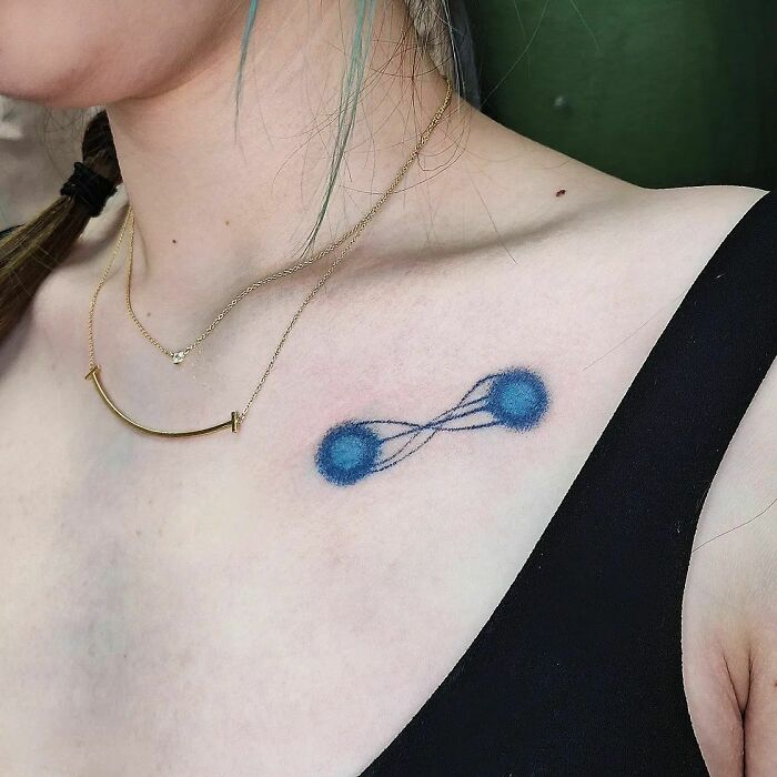 Tattoo of two blue atoms connected by lines, representing science on a shoulder.