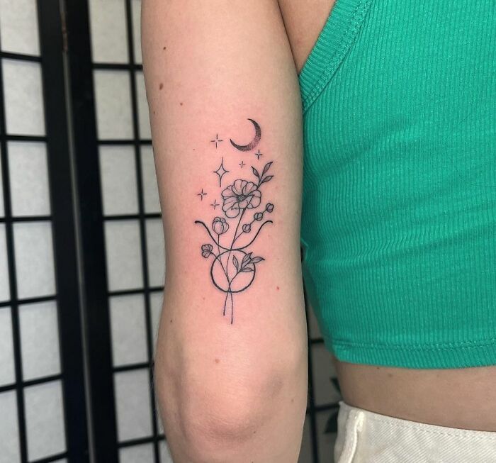 Minimalist zodiac tattoo with floral design and crescent moon on arm.