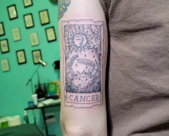 Cancer zodiac tattoo with crab and sun design on forearm.