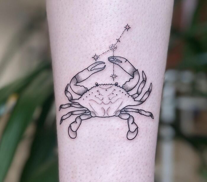 Zodiac tattoo of a crab with stars, representing the Cancer constellation, on a person's forearm.