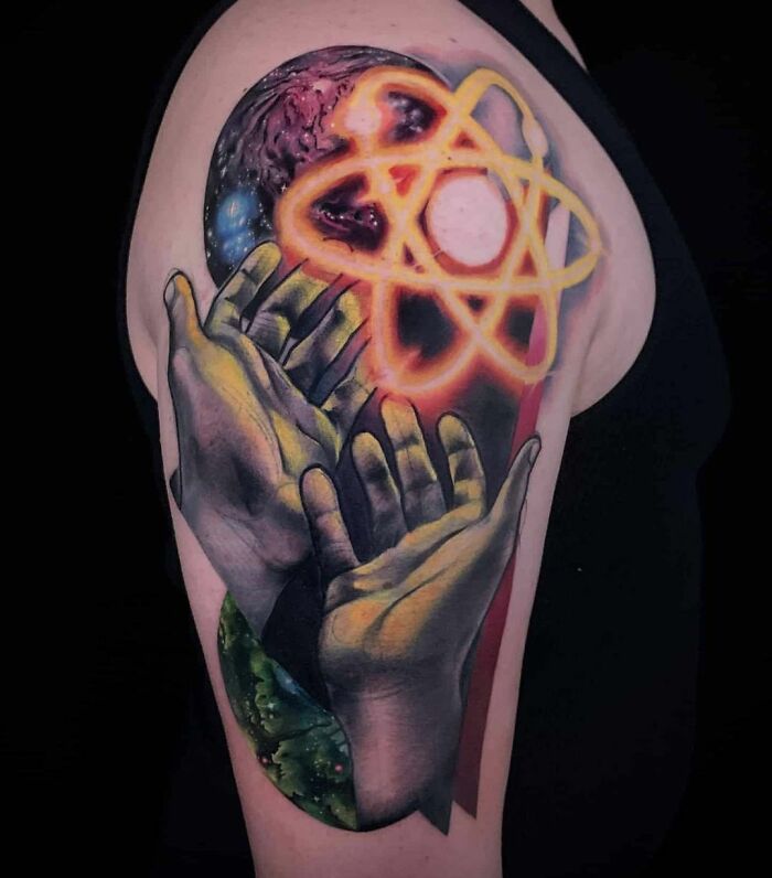Arm tattoo of hands holding a glowing atomic symbol, symbolizing science and cosmic wonders.